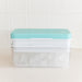 A clear plastic ice cube tray container with a light blue lid and white inner tray, filled with ice cubes, set against a white tiled background.