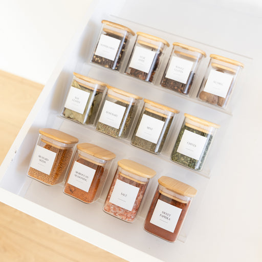 Set of spice jars with wooden lids on a white surface