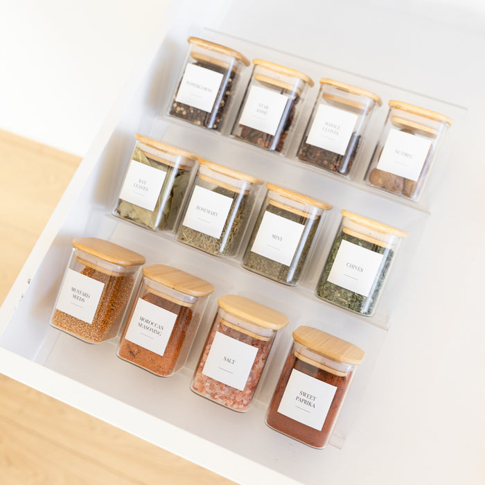 Set of spice jars with wooden lids on a white surface
