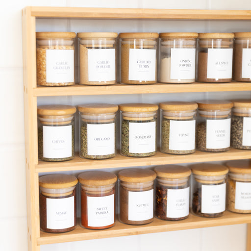 Wooden shelf with jars labeled with white labels on a light background